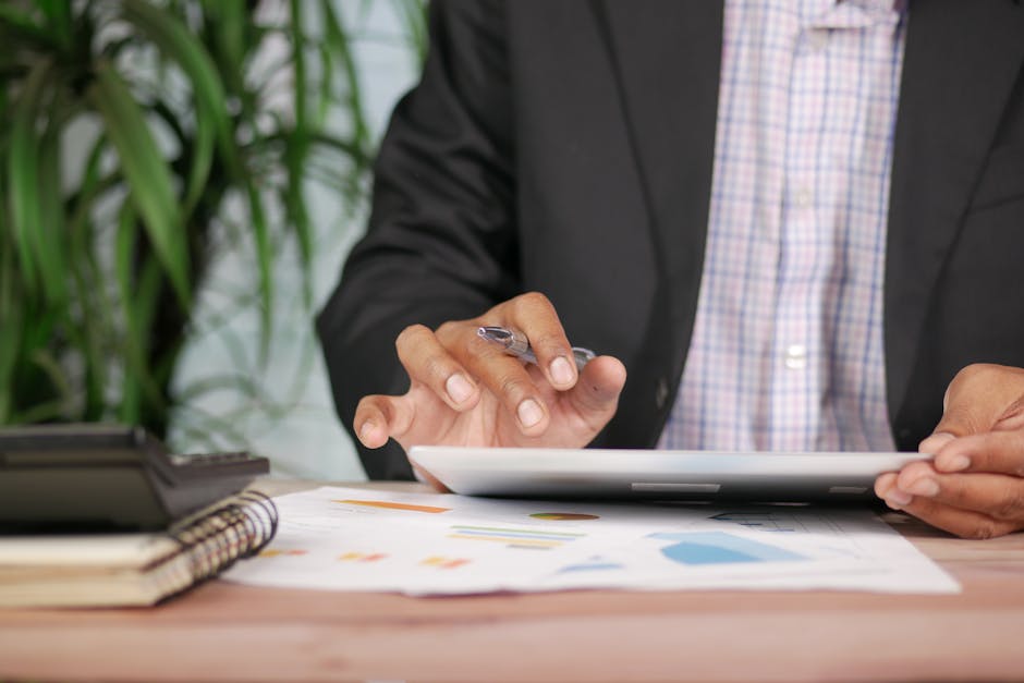 Business professional in suit using tablet with pen on desk with documents and calculator.